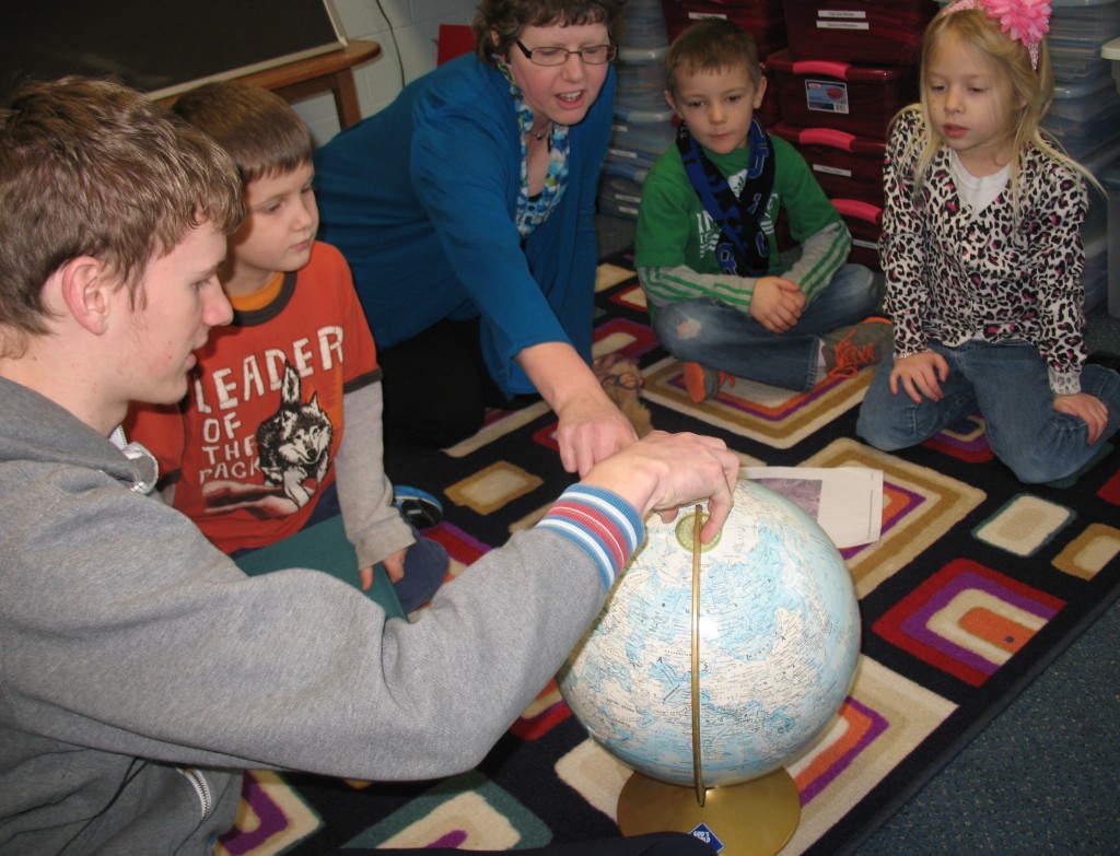 MOUNTAIN LAKE CHRISTIAN junior Aaron Walzak, left, along with the school's kindergarten teacher, Sheryl Fast, center, help students find the country of Israel on the globe.