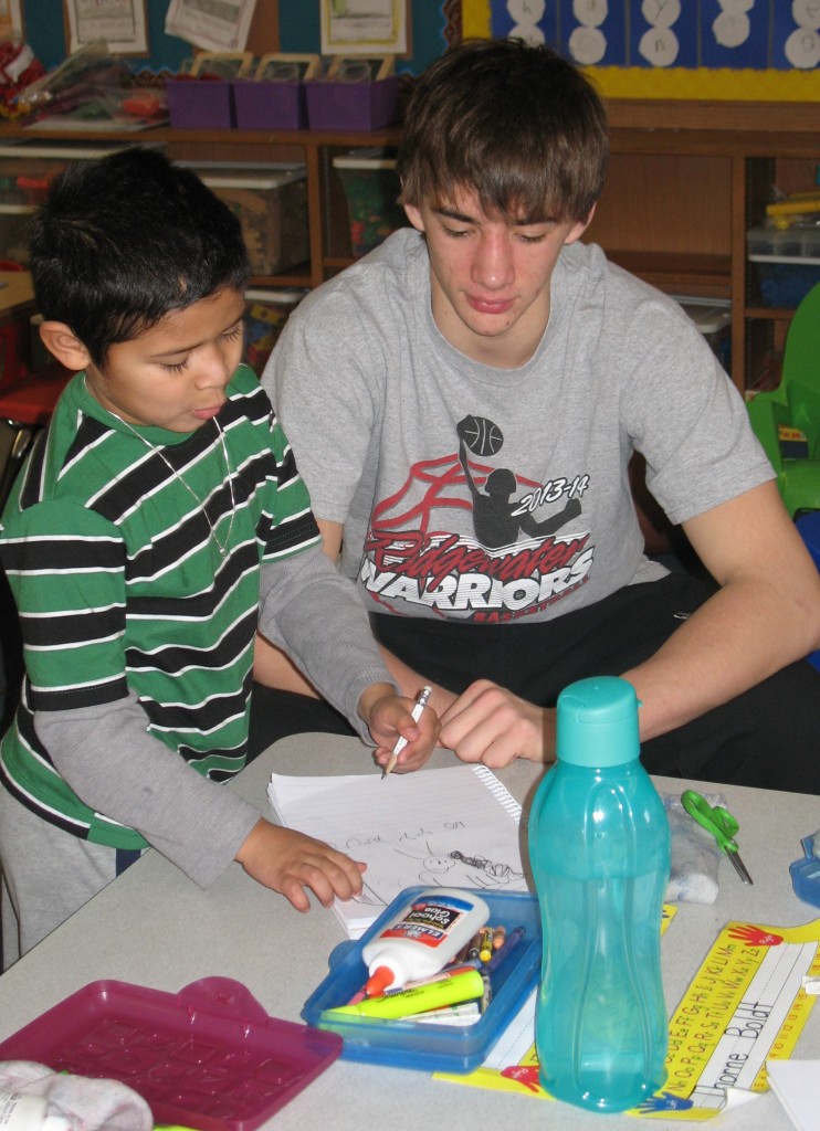 SENIOR ALEX GERDES helps kindergarten students journal in Nicole James' kindergarten class at Mountain Lake Public Elementary.