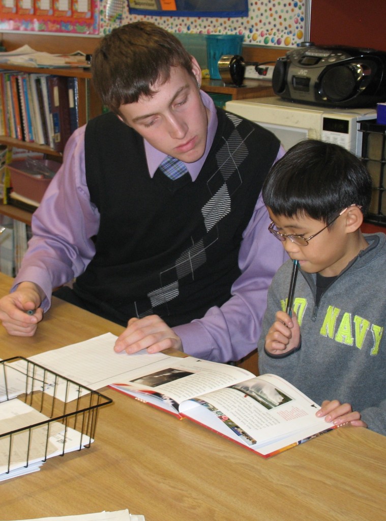 SENIOR LEVI BLAHNIK helps a fourth-grade student with an assignment in Stephanie Willaby's class at Mountain Lake Public Elementary.