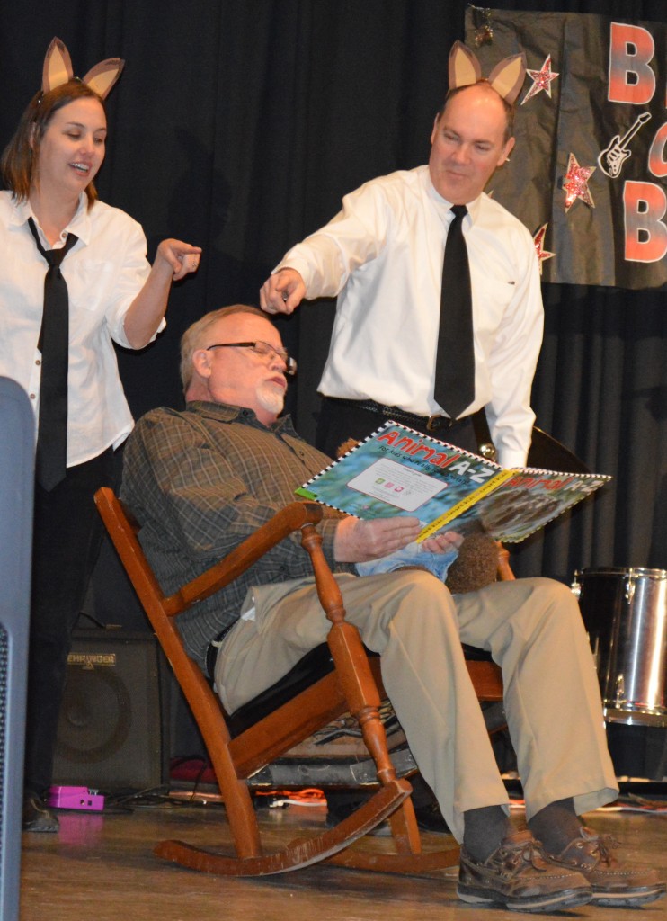 HAUNTING ENGLISH TEACHER Nathan Fast, seated, as he read the story of the fox, the farm animals and the farmer, are ????, left, and Dennis Stade, right.