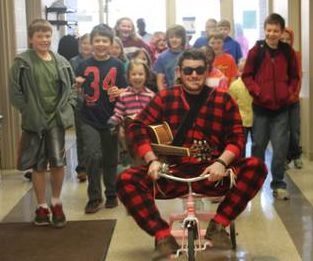 Principal Petersen entered the building with a flurry of excitement this morning wearing footy pajamas, black sunglasses and riding a tricycle.  As the students’ reward for selling 543 boxes of fruit during MLC’s annual fruit fund-raiser, Principal Petersen will perform his duties for the whole day!