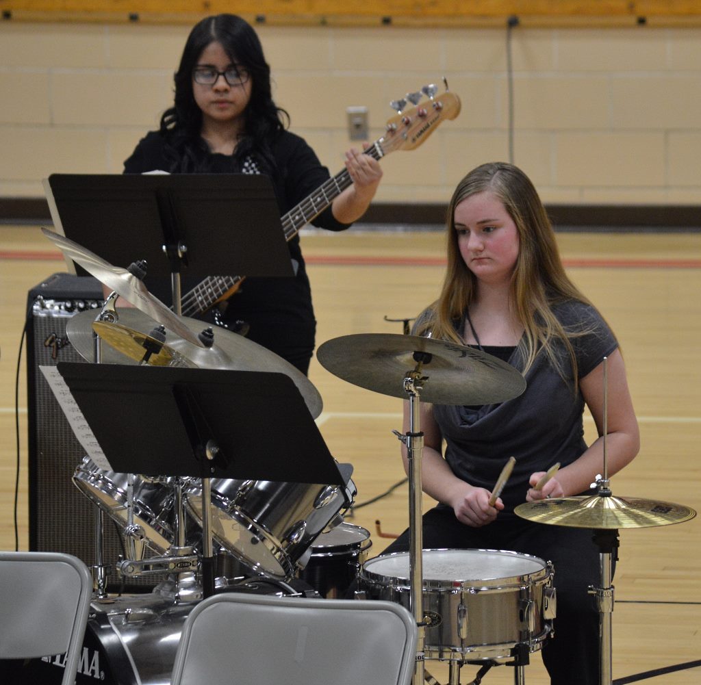 MANNHEIM STEAMROLLER'S "FRESH Aire Christmas" by the Senior High Band. On electric bass guitar is Arely Anaya, left, and on drum set, Brianna Ringen, right.