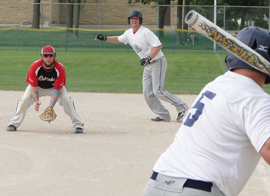 ODIN FIRST-BASE runner Dusty Pfeiffer, right, watches as the ball off the bat of his teammate flies to the right of the Ostrander first baseman, Patrick Brackley, left. 
